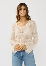 [Color: Natural] A front facing image of a brunette model wearing a beige crochet knit top with long bell sleeves and a v-neckline. A breezy beach top for spring and summer. 