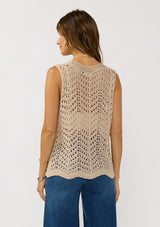 [Color: Natural] A back facing image of a brunette model wearing a beige crochet knit vest with a tie front. 
