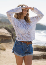 [Color: White] A side facing image of a blonde model wearing a white crochet knit top with a round neckline and long sleeves. A breezy pullover for the beach or casual outings. 