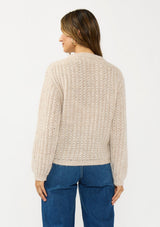 [Color: Heather Taupe] A back facing image of a brunette model wearing a beige cardigan with a button front and crew neckline. 