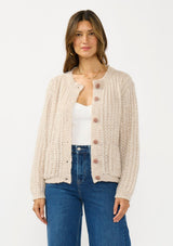 [Color: Heather Taupe] A front facing image of a brunette model wearing a beige cardigan with a button front and crew neckline. 