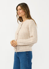 [Color: Heather Taupe] A side facing image of a brunette model wearing a beige cardigan with a button front and crew neckline. 