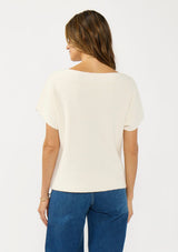 [Color: Natural] A back facing image of a brunette model wearing a white sweater top with short sleeves and a boat neckline. 