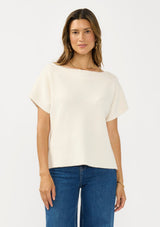 [Color: Natural] A front facing image of a brunette model wearing a white sweater top with short sleeves and a boat neckline. 