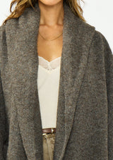 [Color: Dark Heather Brown] A detail image of a brunette model wearing a brown cozy wool blend coatigan with an oversized fit, hoodie, and side pockets. 