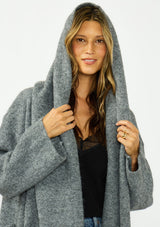 [Color: Heather Charcoal] A detail image of a brunette model wearing a grey cozy wool blend coatigan with an oversized fit, hoodie, and side pockets. 