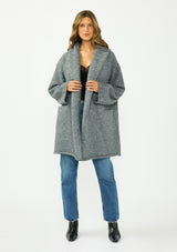 [Color: Heather Charcoal] A front facing image of a brunette model wearing a grey cozy wool blend coatigan with an oversized fit, hoodie, and side pockets. 