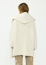 [Color: Heather Cream] A back facing image of a brunette model wearing a cream cozy wool blend coatigan with an oversized fit, hoodie, and side pockets. 