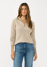 [Color: Heather Cement] A front image of a brunette model wearing a brown pointelle knit sweater with a half zip up. 