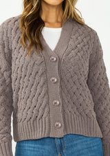 [Color: Mocha] A detail image of a brunette model wearing a knit cardigan with a button front and v neckline. Paired with dark brown denim. 