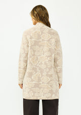 [Color: Taupe] A back facing image of a brunette model wearing a light beige floral cardigan with an open front and patch pockets. 