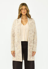 [Color: Taupe] A front facing image of a brunette model wearing a light beige floral cardigan with an open front and patch pockets. 