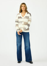 [Color: Ivory/Taupe] A front facing image of a brunette model wearing a fuzzy striped cardigan with a v neckline, dropped shoulders, and a button front. Styled with a dark wash denim and black loafers.