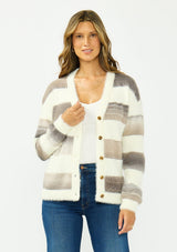 [Color: Ivory/Taupe] A front facing image of a brunette model wearing a fuzzy striped cardigan with a v neckline, dropped shoulders, and a button front. 