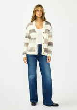 [Color: Ivory/Taupe] A front facing image of a brunette model wearing an open fuzzy striped cardigan with a v neckline, dropped shoulders, and a button front. 