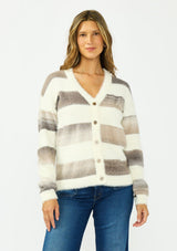 [Color: Ivory/Taupe] A front facing image of a brunette model wearing a fuzzy striped cardigan with a v neckline, dropped shoulders, and a button front. 
