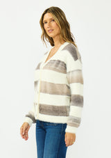 [Color: Ivory/Taupe] A side facing image of a brunette model wearing a fuzzy striped cardigan with a v neckline, dropped shoulders, and a button front. 