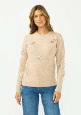 [Color: Heather Sand] A front facing image of a brunette model wearing a light brown crew neck sweater with sequins and embellishment. 