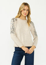 [Color: Oatmeal] A front facing image of a blonde model wearing a speckled beige pullover sweater with a crew neckline and sequins along the shoulder.