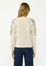 [Color: Oatmeal] A back facing image of a blonde model wearing a speckled beige pullover sweater with a crew neckline and sequins along the shoulder.