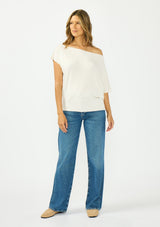 [Color: Natural] A front facing image a brunette model wearing an off white off the shoulder sweater top with short sleeves and a fitted ribbed hem. 