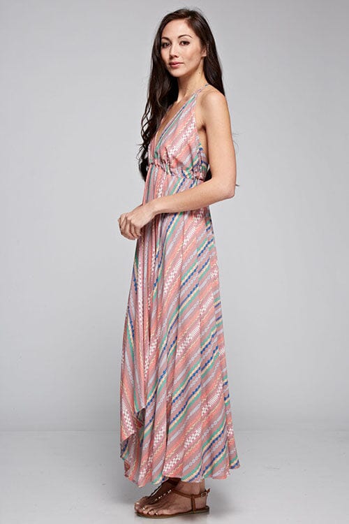 [Color: Brick Multi] A brunette model wearing a boho striped geo print halter maxi dress with a flowy shark bite skirt, open back, and a flattering v-neckline. 