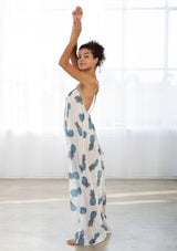 [Color: Blue/Ivory] A side facing image of a brunette model wearing a sheer blue and white pineapple print maxi dress with a scoop neckline and adjustable spaghetti straps, and strappy back design.