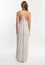 [Color: Nude Combo] A back facing image of a blonde model  wearing a bohemian maxi dress with a halter neckline and a racerback with tassel ties.