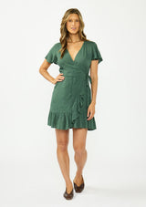 [Color: Forest Green] A front facing image of a brunette model wearing a green embroidered wrap dress with short sleeves, a ruffle trimmed hem, and a side tie detail. 