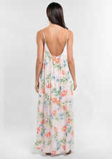 [Color: Blush/Green] A back facing image of a brunette model wearing a tropical floral print maxi dress with a high low hemline, a scoop neckline, and spaghetti straps. 