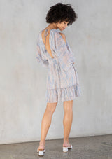 [Color: Sky Natural] A back facing image of a brunette model wearing a boho mini dress with an abstract print, split sleeves, a v neckline, smocked waist, and a tassel tie back detail. 