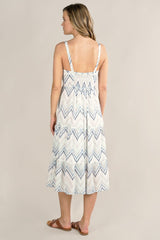 [Color: White/Blue] A back facing image of a blonde model wearing a white and blue chevron pattern midi dress with all over eyelet details. Featuring a sleeveless design, a v-neckline, smocked back, button front top, and flowy tiered skirt. 