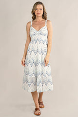 [Color: White/Blue] A front facing image of a blonde model wearing a white and blue chevron pattern midi dress with all over eyelet details. Featuring a sleeveless design, a v-neckline, smocked back, button front top, and flowy tiered skirt. 
