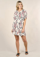 [Color: Ivory Orchid] A front facing image of a blonde model wearing a pink and blue floral print mini dress with a button front top, short dolman sleeves, and a smocked waistline. 