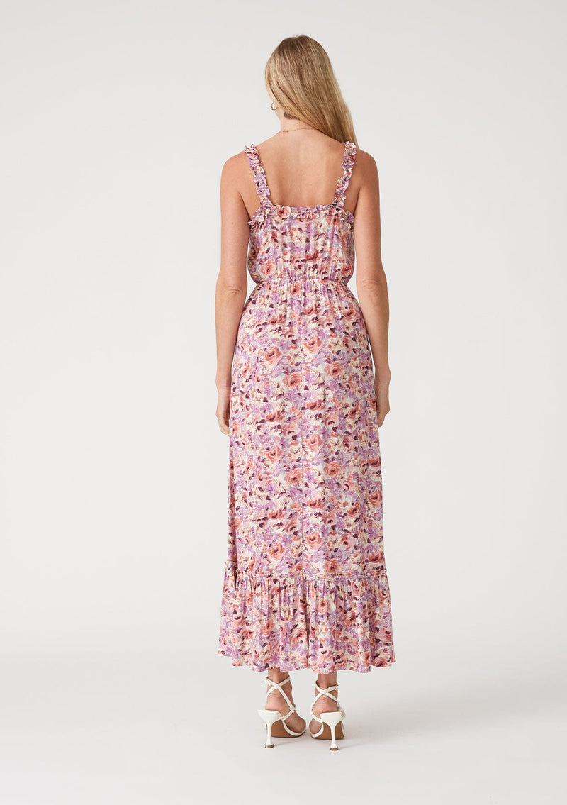 [Color: Dusty Purple/Taupe] A back facing image of a blonde model wearing a pink and purple floral print maxi dress. With ruffled tank top straps, a ruffle trimmed square neckline, an elastic waist, a tiered long skirt, and a lace up top. 