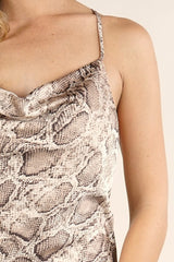 [Color: Ivory Mocha] A detail image of a blonde model wearing brown  snake print midi dress  with a cowl neckline. 