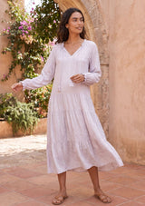 [Color: Orchid Tint] A model wearing an elegant and classic light purple bohemian peasant maxi dress in floral jacquard. Featuring a dropped waist, a tiered skirt, and a split v neckline with tassel ties.
