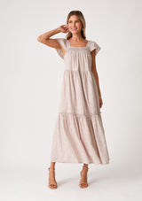 [Color: Dusty Lavender] A front facing image of a blonde model wearing a dreamy bohemian cotton blend maxi dress in a light lavender. With a smocked square neckline, short flutter cap sleeves, and a ruffle trimmed tiered hemline.