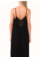 [Color: Black] A close up back facing image of a blonde model wearing a black summer bohemian maxi tank dress. With adjustable spaghetti straps, a v neckline, a flowy fit, and a soutache braided detail at the back.
