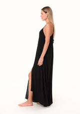 [Color: Black] A side facing image of a blonde model wearing a black summer bohemian maxi tank dress. With adjustable spaghetti straps, a v neckline, a flowy fit, and a soutache braided detail at the back.