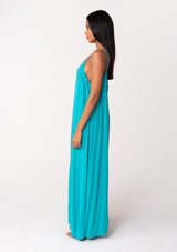 [Color: Turquoise] A side facing image of a brunette model wearing a turquoise blue summer bohemian maxi tank dress. With adjustable spaghetti straps, a v neckline, a flowy fit, and a soutache braided detail at the back. 
