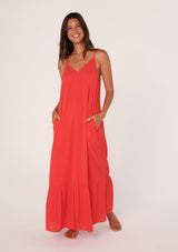 [Color: Flame] A front facing image of a brunette model wearing a simple flowy sleeveless maxi tank dress in a bright red crinkle rayon. With a v neckline in front and back, adjustable spaghetti straps, and a tiered skirt.