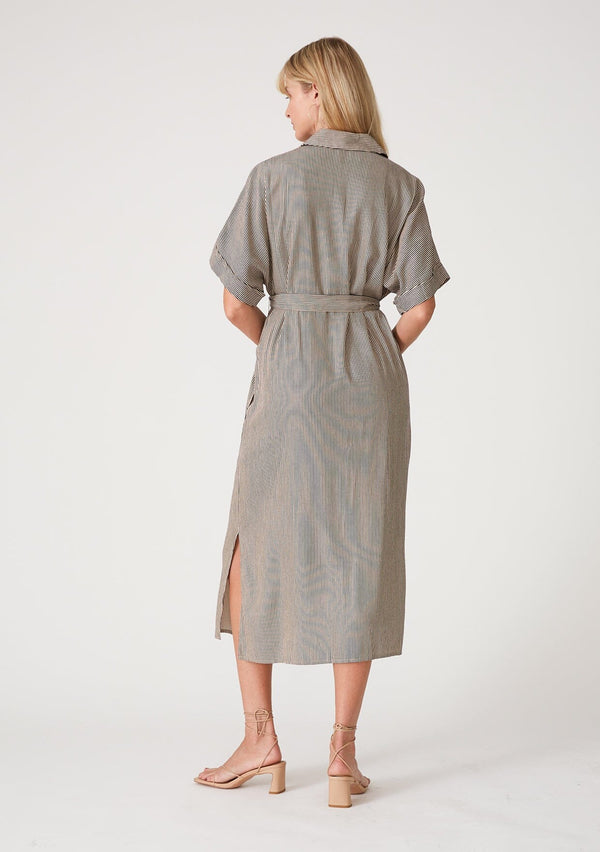 [Color: Taupe/Navy] A back facing image of a blonde model wearing a relaxed fit mid length shirt dress in a taupe and navy blue stripe. With short dolman sleeves, a collared neckline, a concealed button front, side pockets, a waist belt, and side slits. 