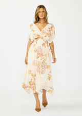 [Color: Ivory/Rust] A front facing image of a brunette model wearing an ivory and orange floral dress with a surplice v neckline, short dolman sleeves, an open tie back detail, and an asymmetrical hem. 