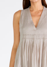[Color: Grey] A close up front facing image of a brunette model wearing a lightweight bohemian sleeveless maxi tent dress in grey. With a v neckline, pleated details, and side pockets.