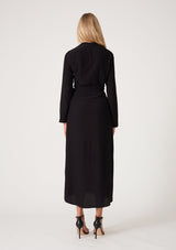 [Color: Black] A back facing image of a blonde model wearing a sophisticated black mid length wrap dress with long sleeves, a v neckline, a side slit, and a side tie waist. 