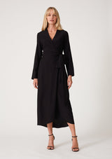 [Color: Black] A front facing image of a blonde model wearing a sophisticated black mid length wrap dress with long sleeves, a v neckline, a side slit, and a side tie waist. 