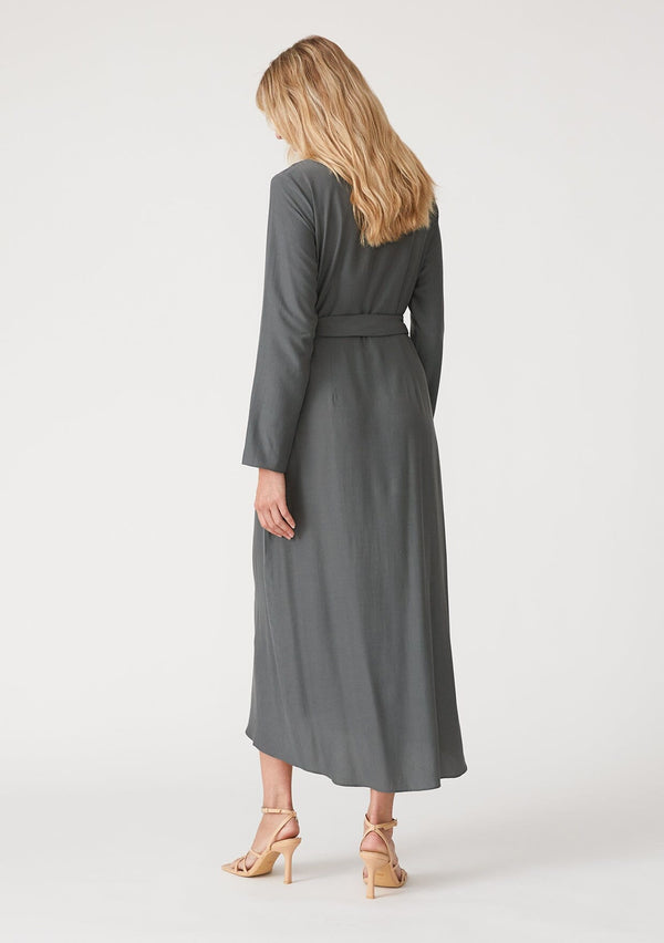[Color: Moss] A back facing image of a blonde model wearing a sophisticated moss green mid length wrap dress with long sleeves, a v neckline, a side slit, and a side tie waist.