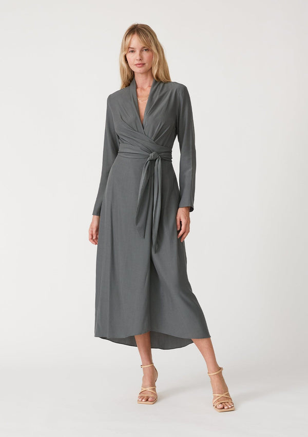 [Color: Moss] A front facing image of a blonde model wearing a sophisticated moss green mid length wrap dress with long sleeves, a v neckline, a side slit, and a side tie waist.
