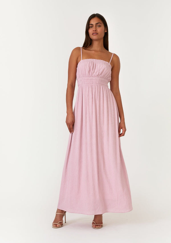 [Color: Orchid] A front facing image of a brunette model wearing an orchid purple sleeveless maxi dress with gold metallic thread details. With a ruffle trimmed straight neckline, an elastic waist, adjustable spaghetti straps, and a long flowy skirt. 